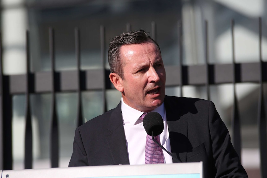WA Premier Mark McGowan speaks at a podium in front of the stadium.