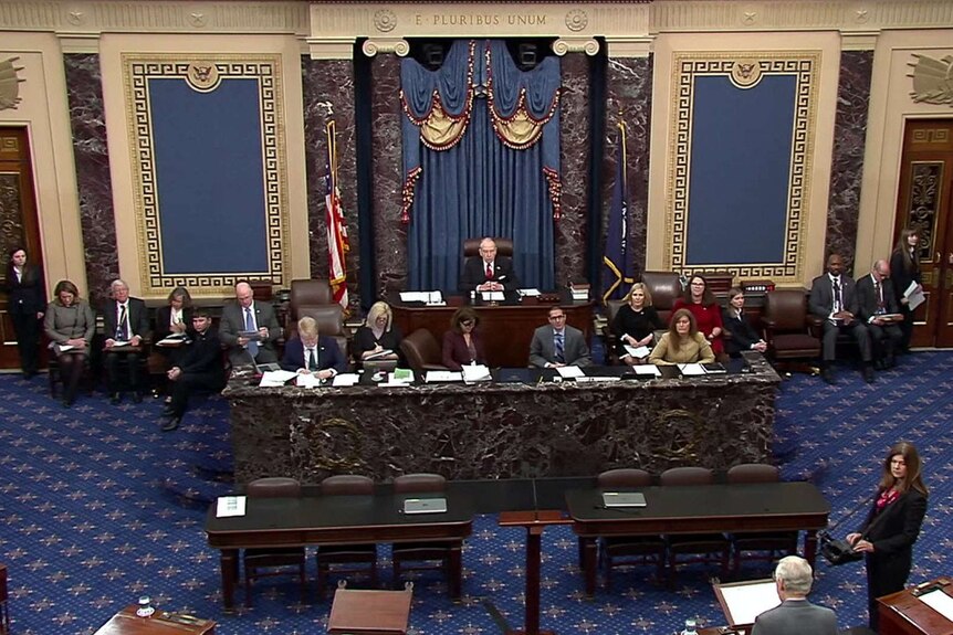 The US Senate chambers set up for a trial. There is a committee sitting at raised tables facing the room.