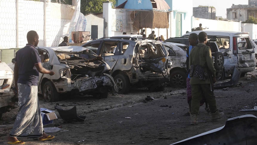 Residents walk past the scene of a bomb attack at Lido beach, Mogadishu