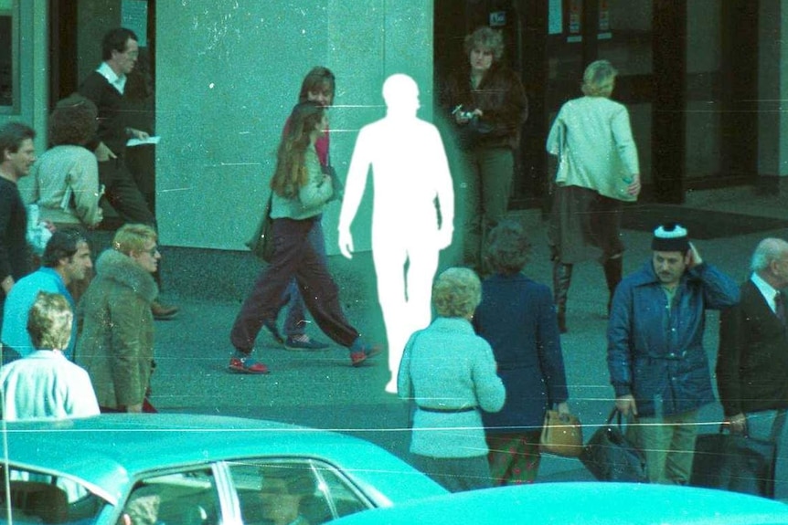 A white outline walks among pedestrians crossing and waiting in central Sydney.