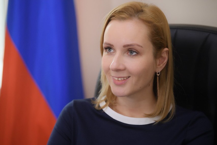Close up of blonde while woman with Russian flag in background.