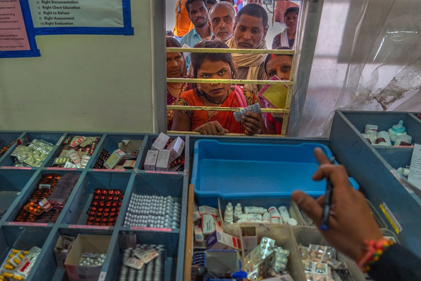 Aanchal Prakash listens to a pharmacist's instructions as she looks through a window to receive medicine