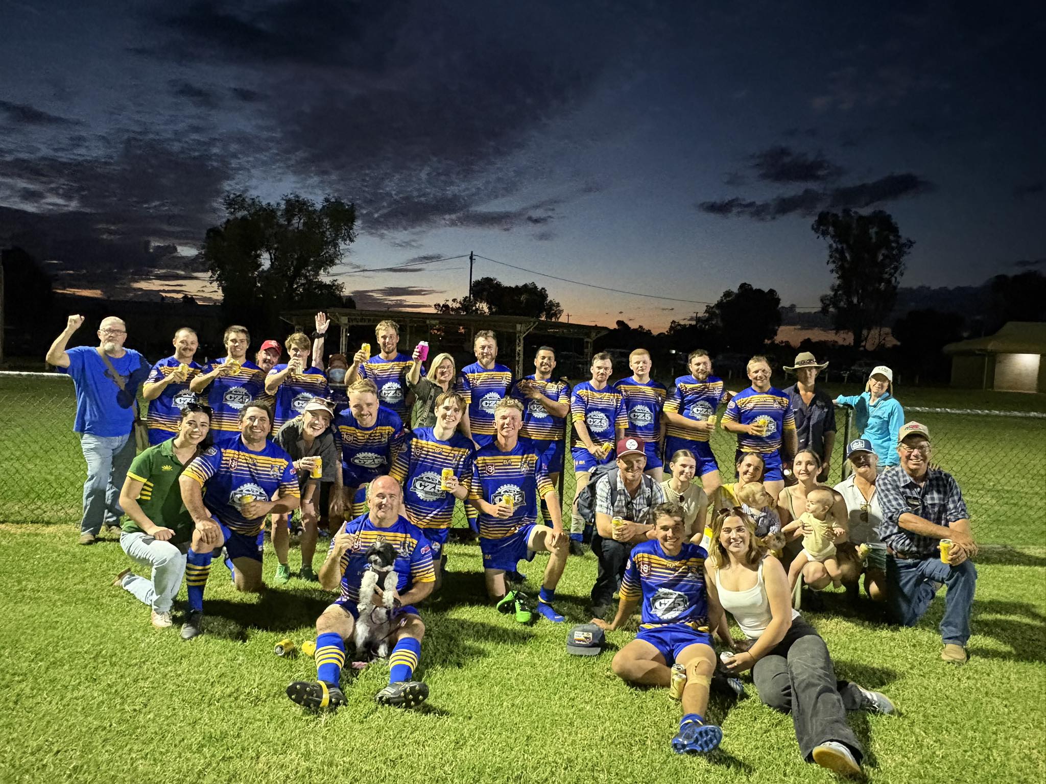 Football players standing and sitting at a football field for a group photo.