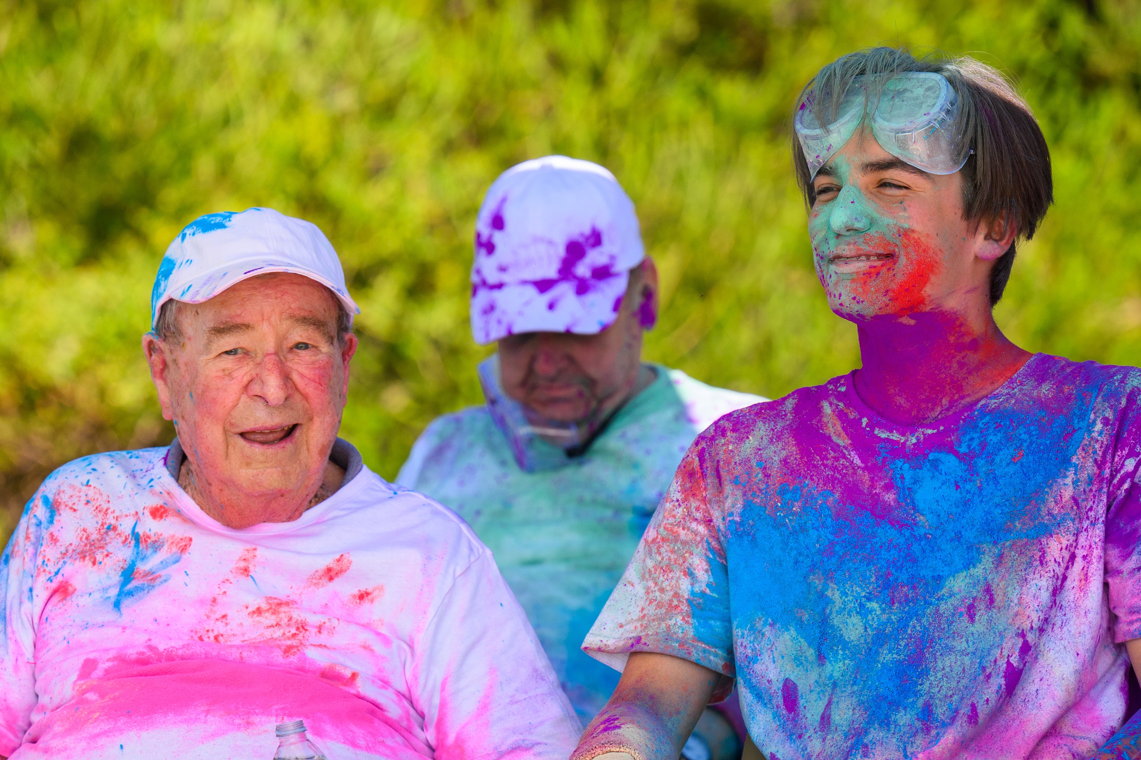 Ken, on the left, and Louis, on the right, wearing white clothes covered in bright colours after doing a colour run
