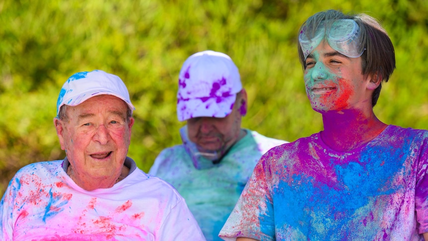 Ken, on the left, and Louis, on the right, wearing white clothes covered in bright colours after doing a colour run