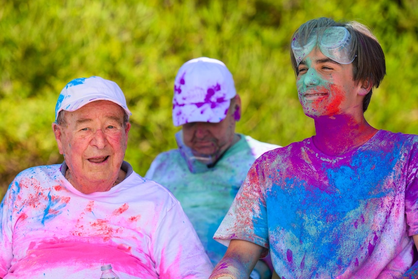 Ken, on the left, and Louis, on the right, wearing white clothes covered in bright colours after doing a colour run