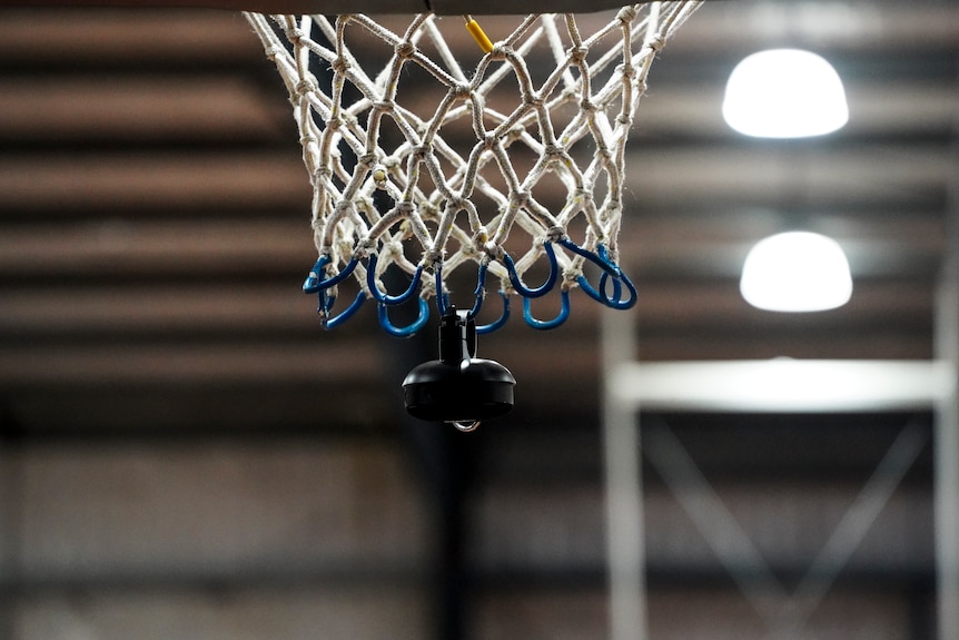 A close up of a basketball net with a bluetooth speaker hanging from the bottom.