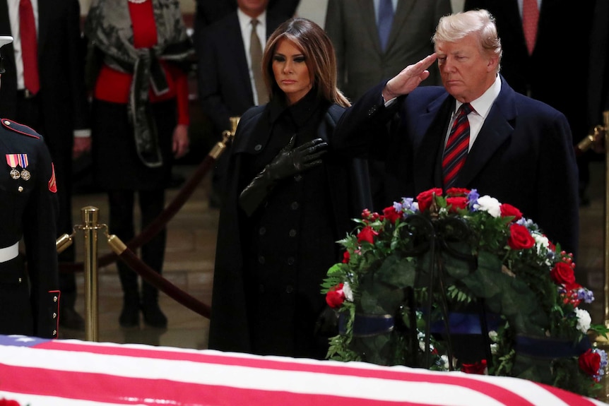 President Trump and Melania Trump salute the coffin of George HW Bush