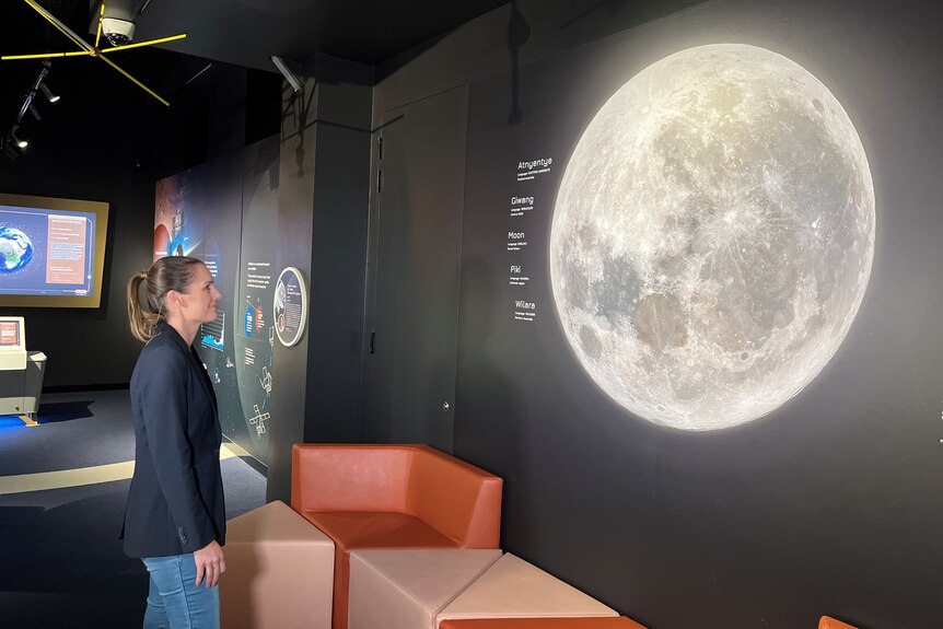 A woman looking at a picture of the moon