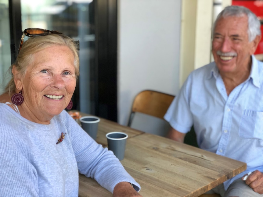 Man and woman sit at a cafe table, smiling