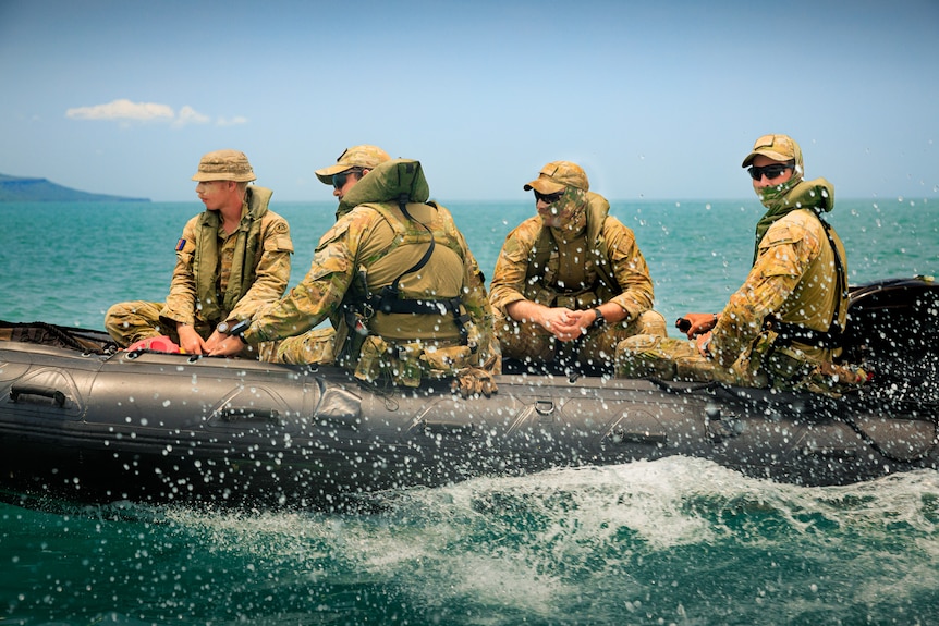 Four soldiers ride in a rubber boat.