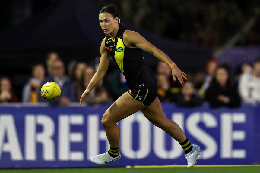 A Richmond AFLW player chases the ball during a match against the Gold Coast Suns.