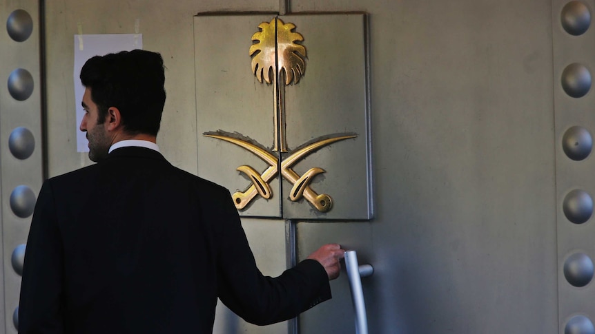 A security guard stands at the door, emblazoned with two crossed swords, to the Saudi Arabian consulate in Turkey.