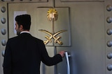 A security guard stands at the door, emblazoned with two crossed swords, to the Saudi Arabian consulate in Turkey.