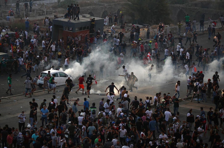 Demonstrators run away from tear gas fired by riot police during a protest following Tuesday's blast.