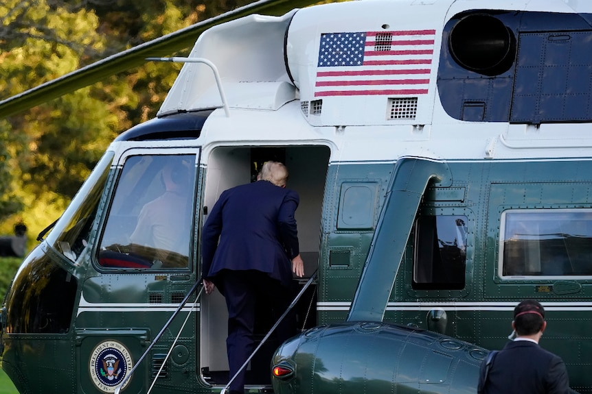 Donald Trump from behind as he walks up steps of Marine One to head to hospital.