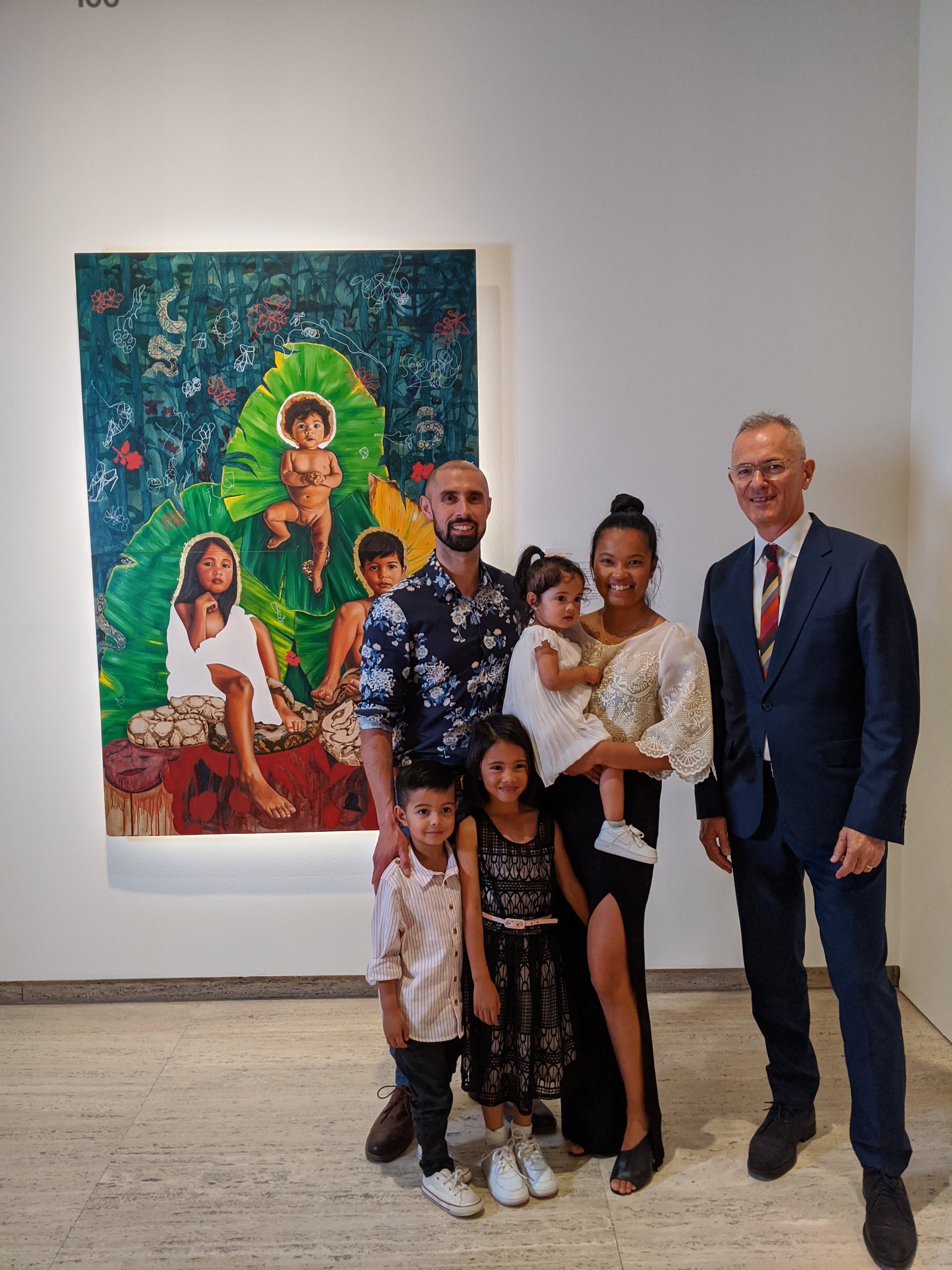 Marikit Santiago poses with her husband and three children, and Michael Brand, in front of a painting of her kids.