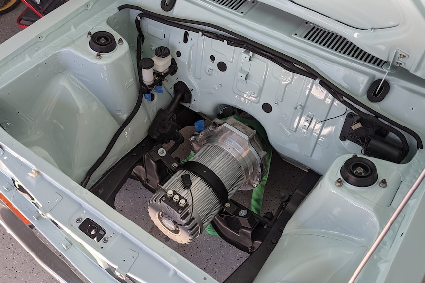 A small electric motor in a much larger engine compartment