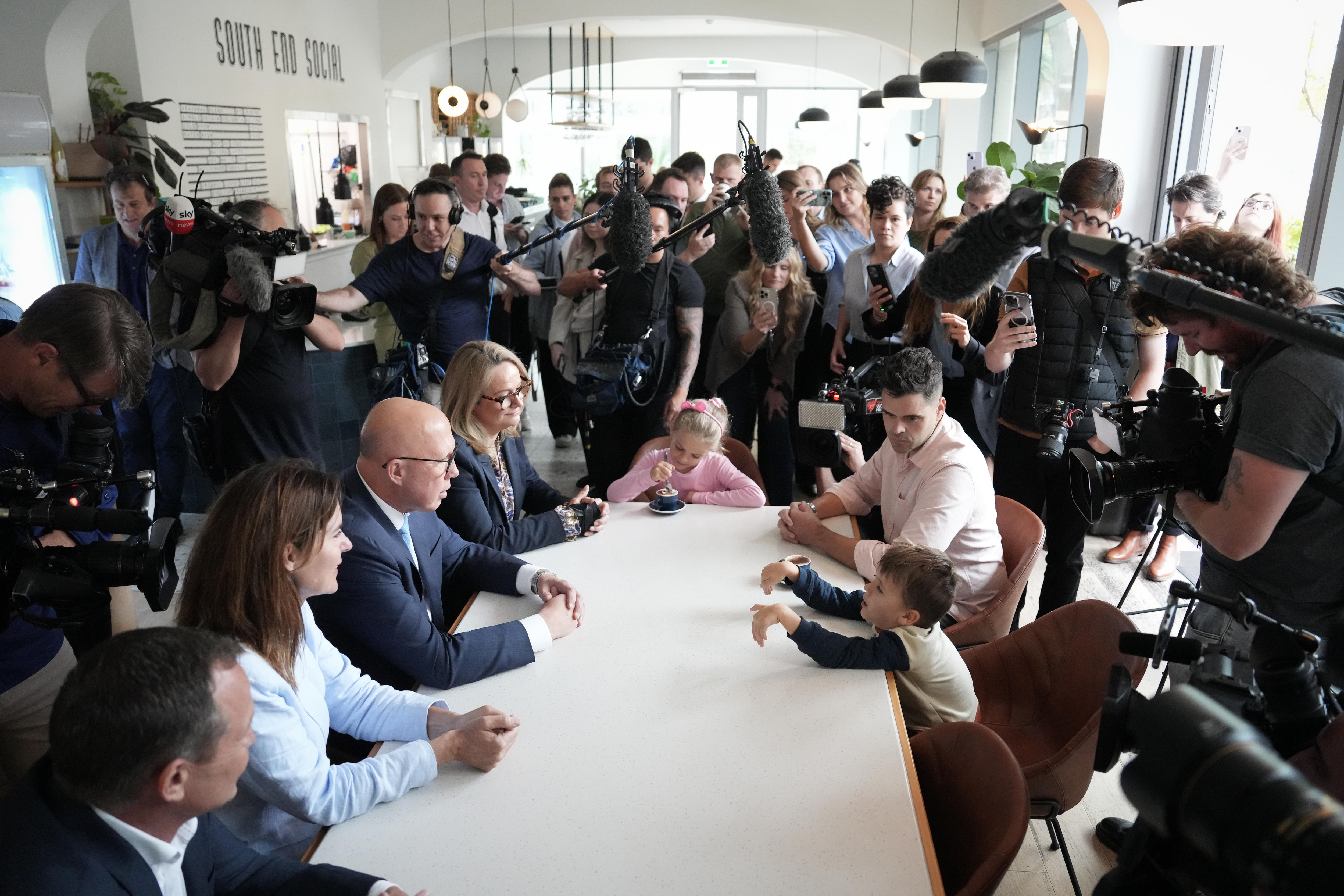 dutton talks to kids at a table surrounded by a huge media pack