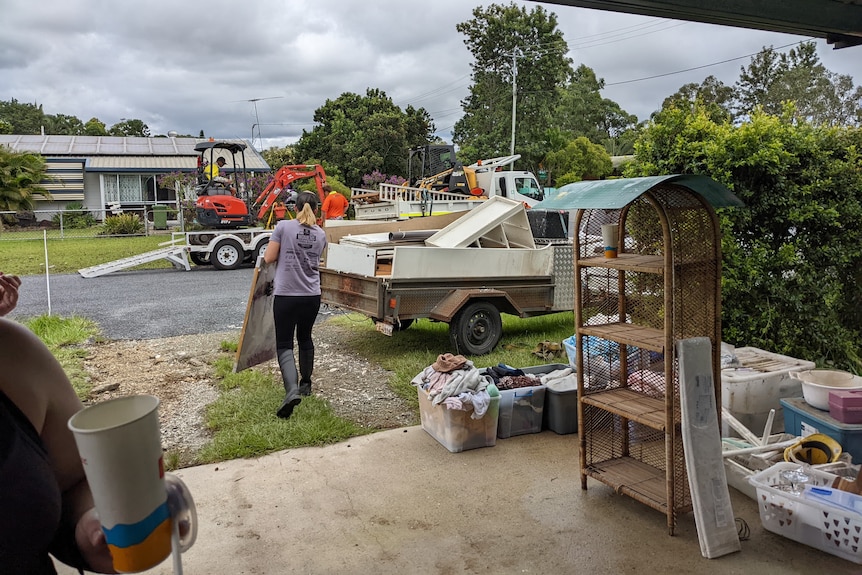 A woman carried out a framed picture onto a driveway full of belongings.