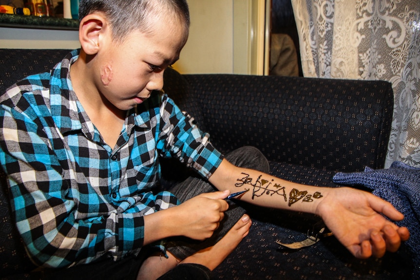 A boy showing his henna designs.