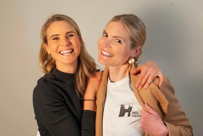 Two blonde women smile at the camera