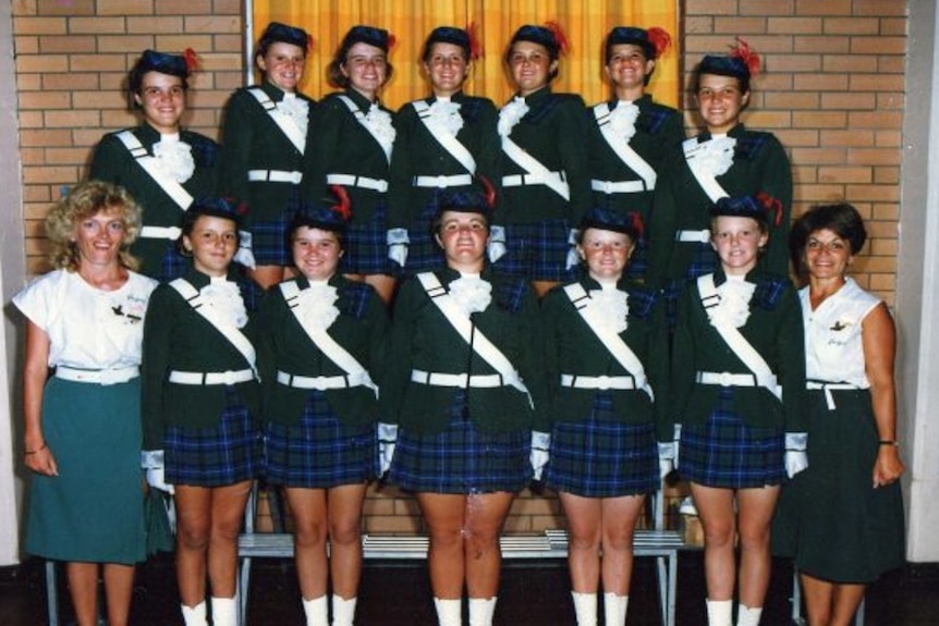 Team photo of girls in blue plaid skirt and green jackets