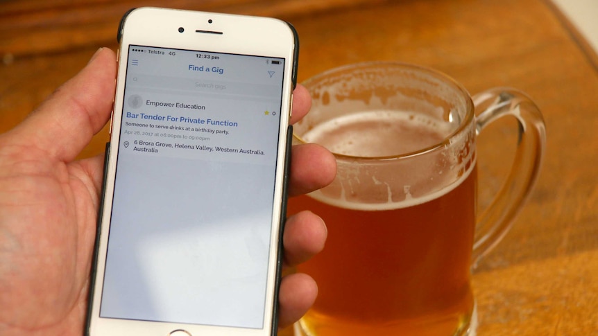 Man holding mobile phone showing squaddle app with a glass of beer on a bar
