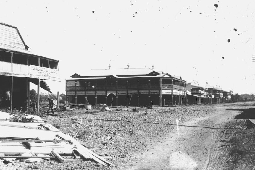 Black and white photo showing the wooden Commercial Hotel with flood debris in the foreground