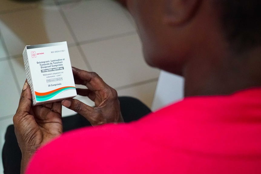 A woman holds a box of HIV antiretrovirals