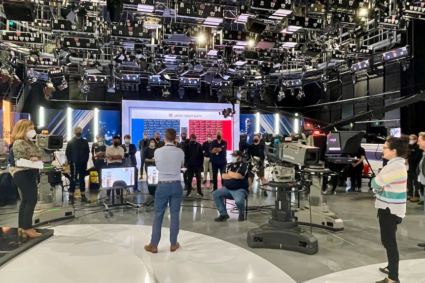 Wide shot of group of people in TV studio.