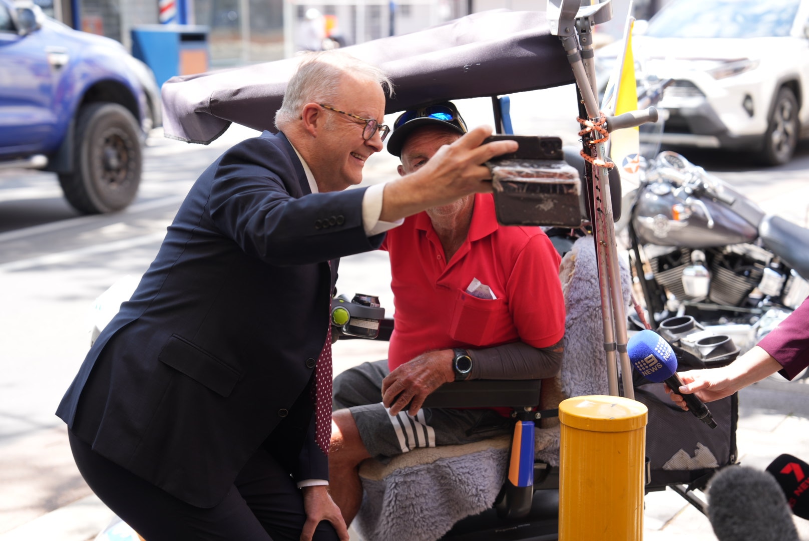 Anthony Albanese takes a selfie of himself and a man sitting outside a cafe