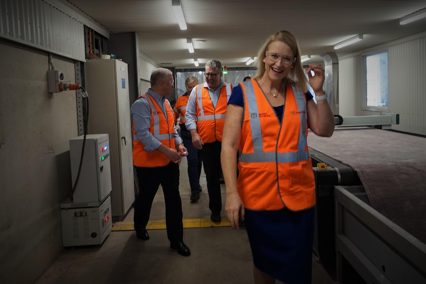 Deputy Chief Minister Nicole Manison wears an orange vest as she walks through a corridor in Darwin at a press conference. 