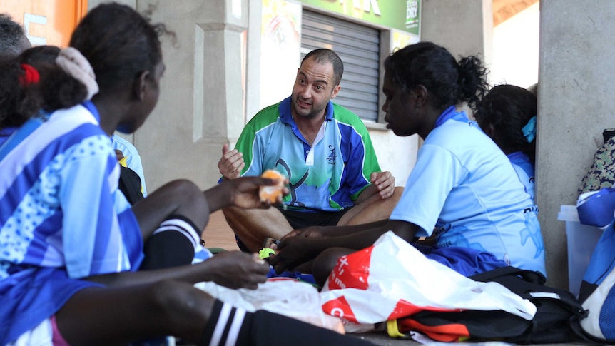 A man coaches a group of young soccer players.