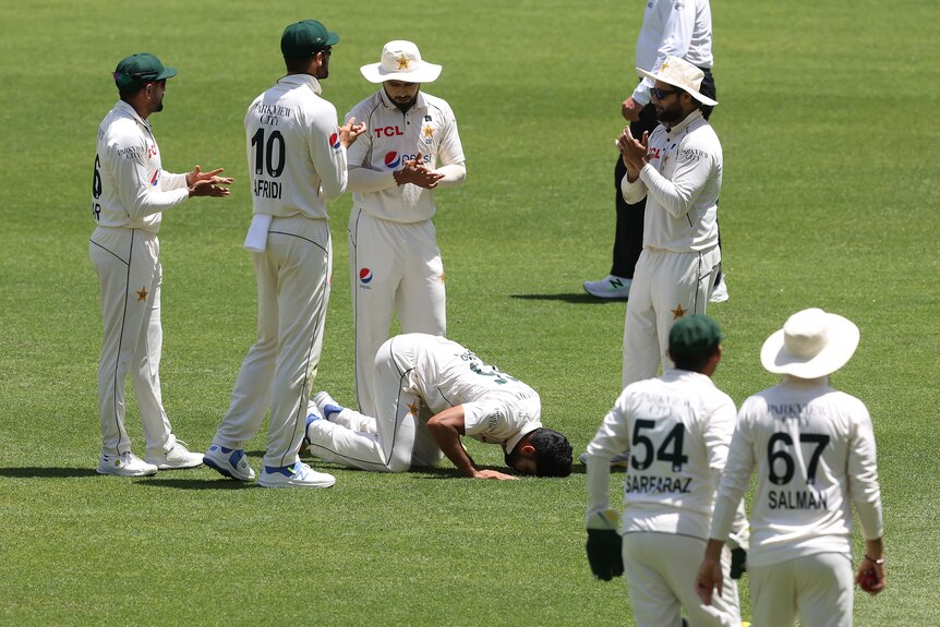 Aamir Jamal met la tête dans l'herbe pendant qu'il prie après avoir remporté six guichets lors d'un test.
