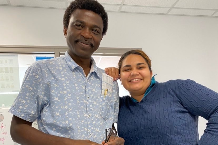 Dr Pam wearing a light blue shirt smiling, Chelsea leaning on his shoulder smiling. 