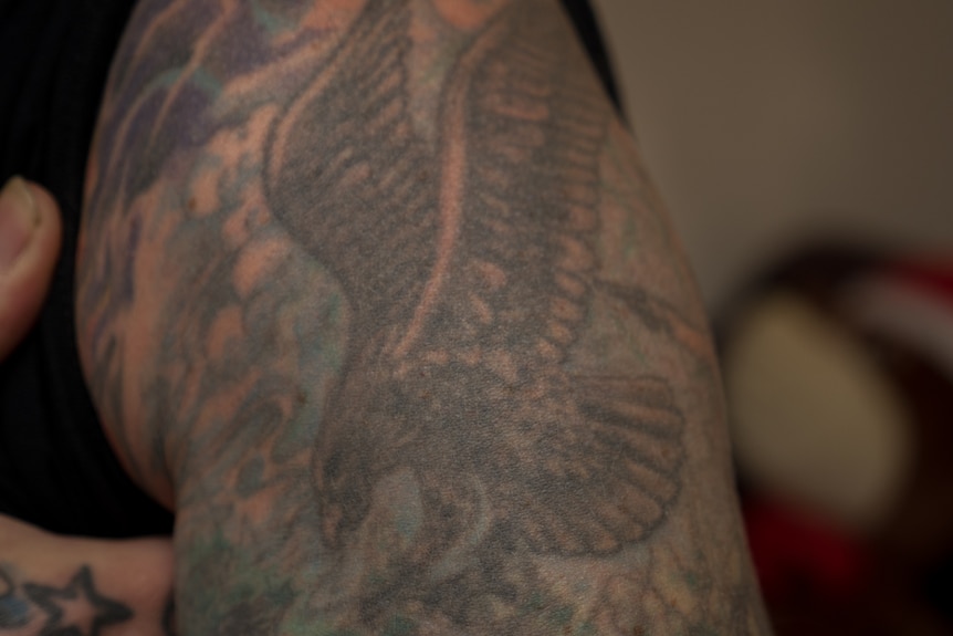 Tattboy shows his first tattoo, an eagle, on his left arm.