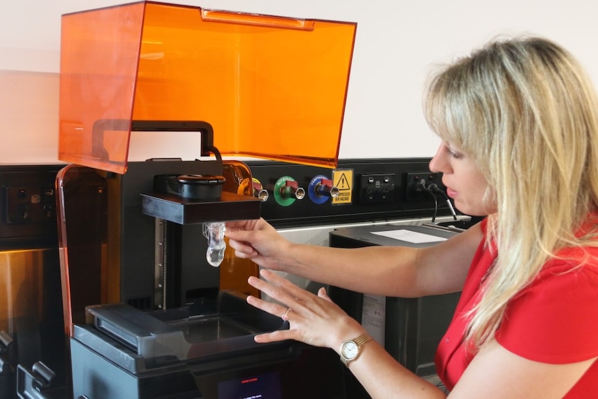 Woman pulls mould out of 3D printer.