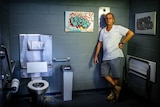 Male artist stands in toilet with mosaic work