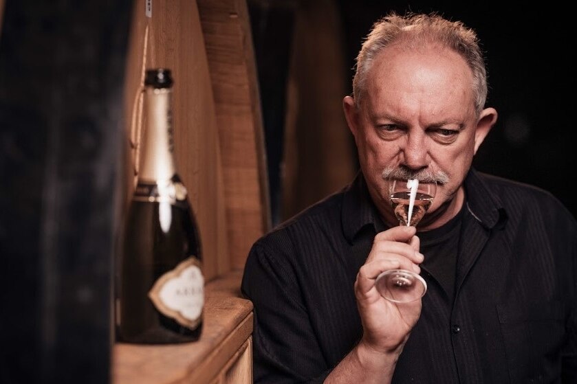 A male winemaker tasting a glass of sparkling wine and examining the colour