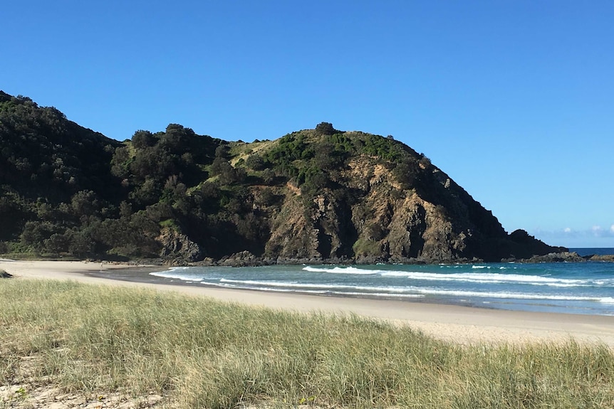 A rocky headline behind a beach.