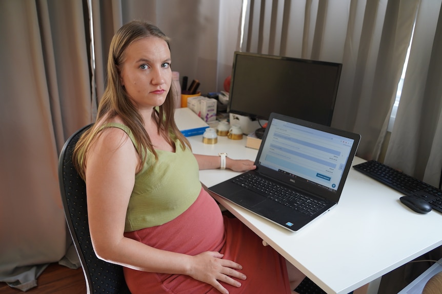 Lotta Helsted, pregnant, sitting at her desk with her laptop open. 