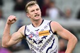 A Fremantle AFL player pumps his right fist after kicking a goal.
