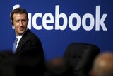 Mark Zuckerberg in front of a Facebook sign