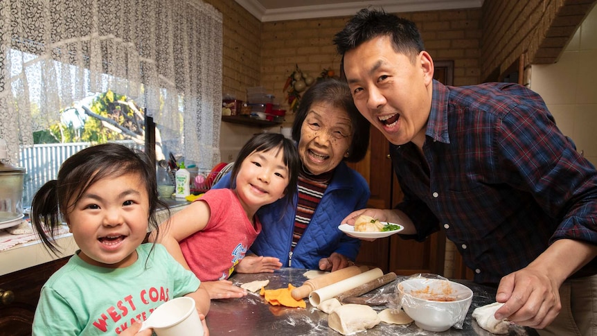 Ann Poon (centre) in the kitchen making dumplings with her great-great granddaughters, Mia and Zoe, and her grandson Matthew.