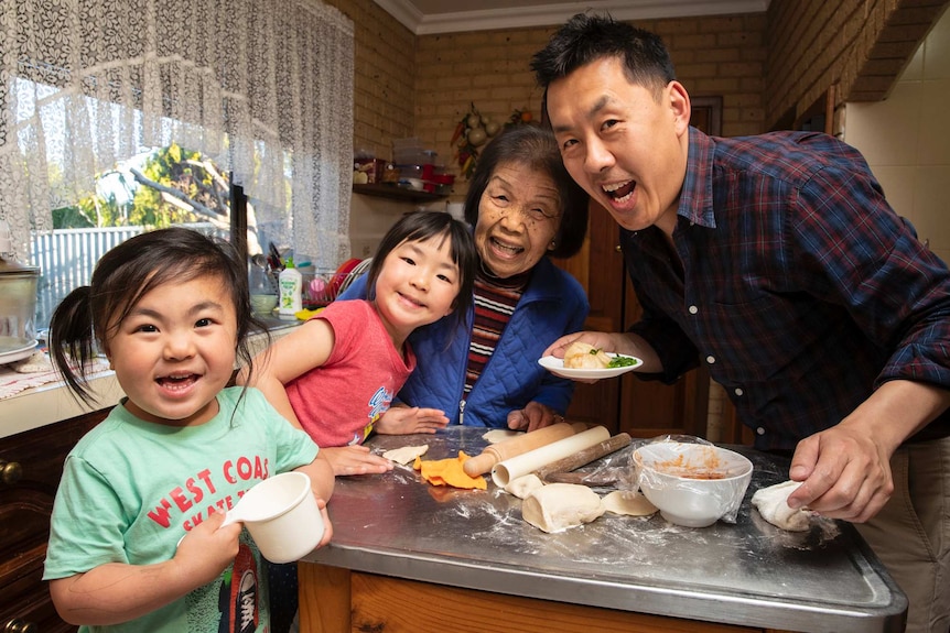 Ann Poon (centre) in the kitchen making dumplings with her great-great granddaughters, Mia and Zoe, and her grandson Matthew.