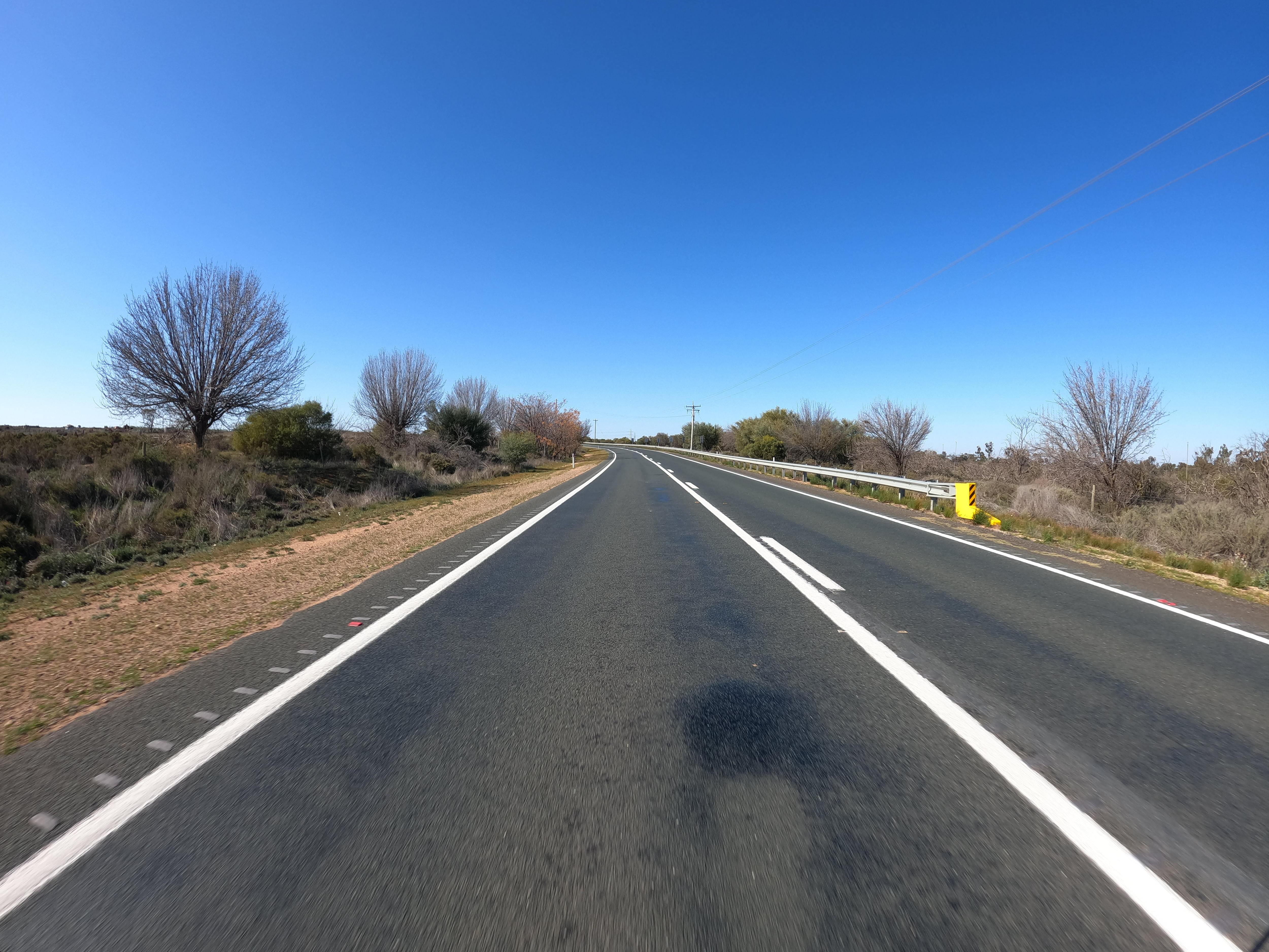 The Sturt Highway, trees off to the side of the road.