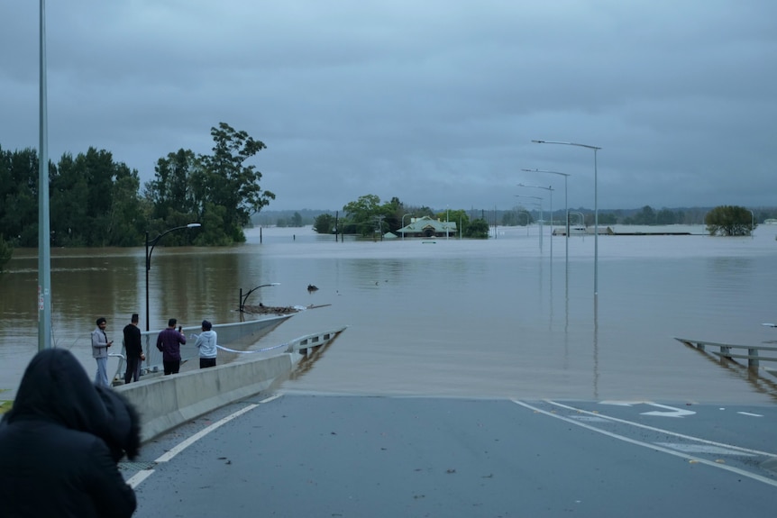 People watching as the road is cut by high waves