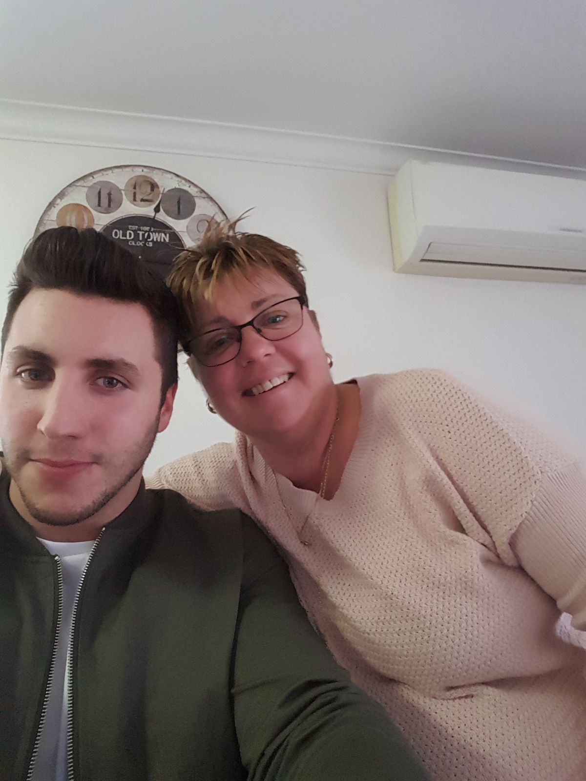 A man poses next to an older woman who leans her head on the man's head.