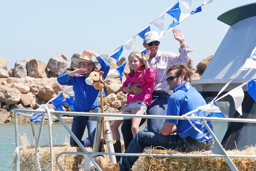 A group of people dressed in costumes waving on a boat 